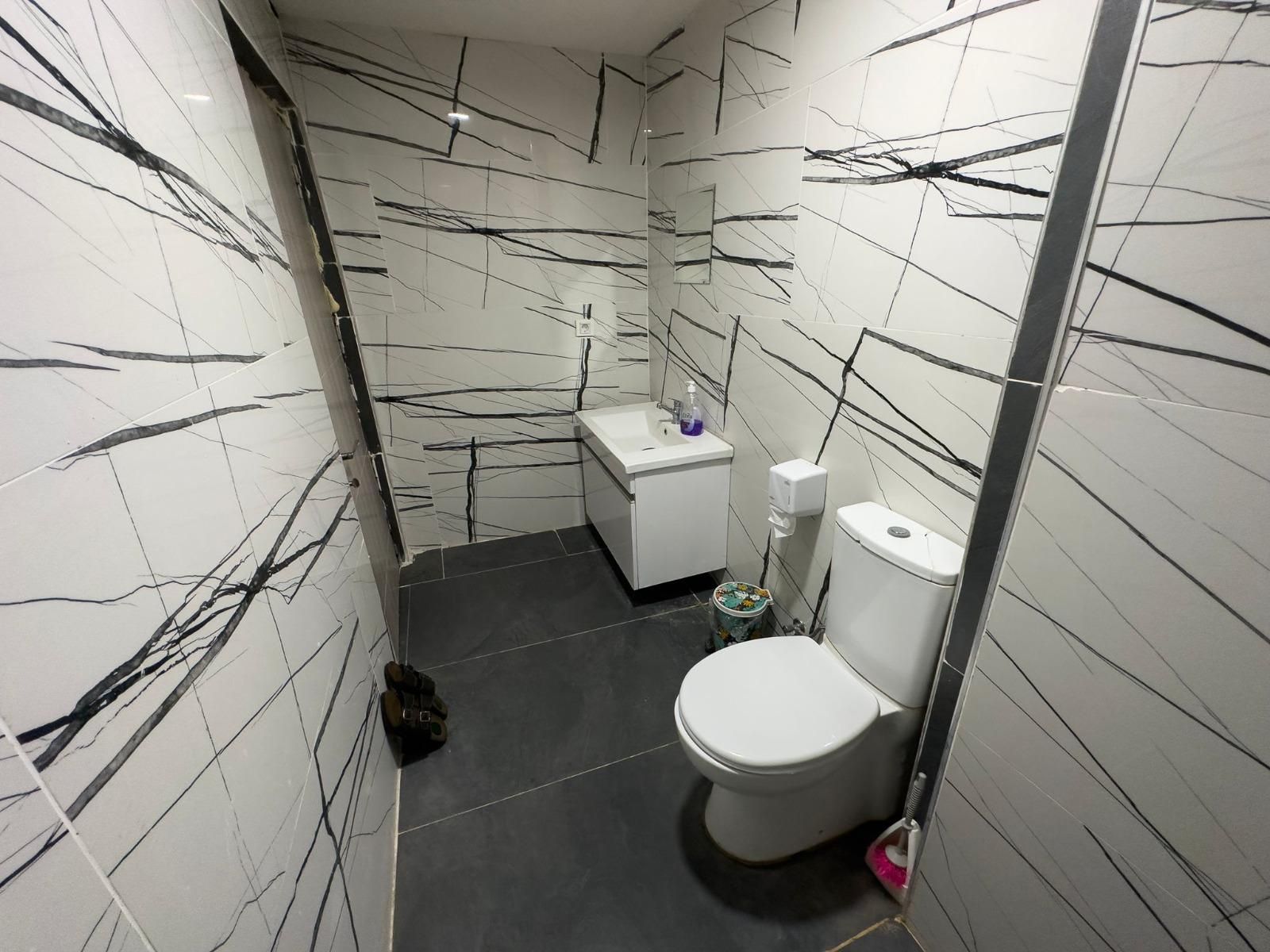 Een badkamer met toilet, wastafel en spiegel.