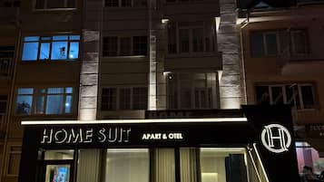 Un edificio a più piani con un cartello ben visibile che riporta 'HOME SULT APART & HOTEL'.