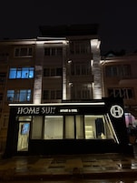 Un edificio de varios pisos con un letrero llamativo que dice 'HOME SULT APART & HOTEL'.