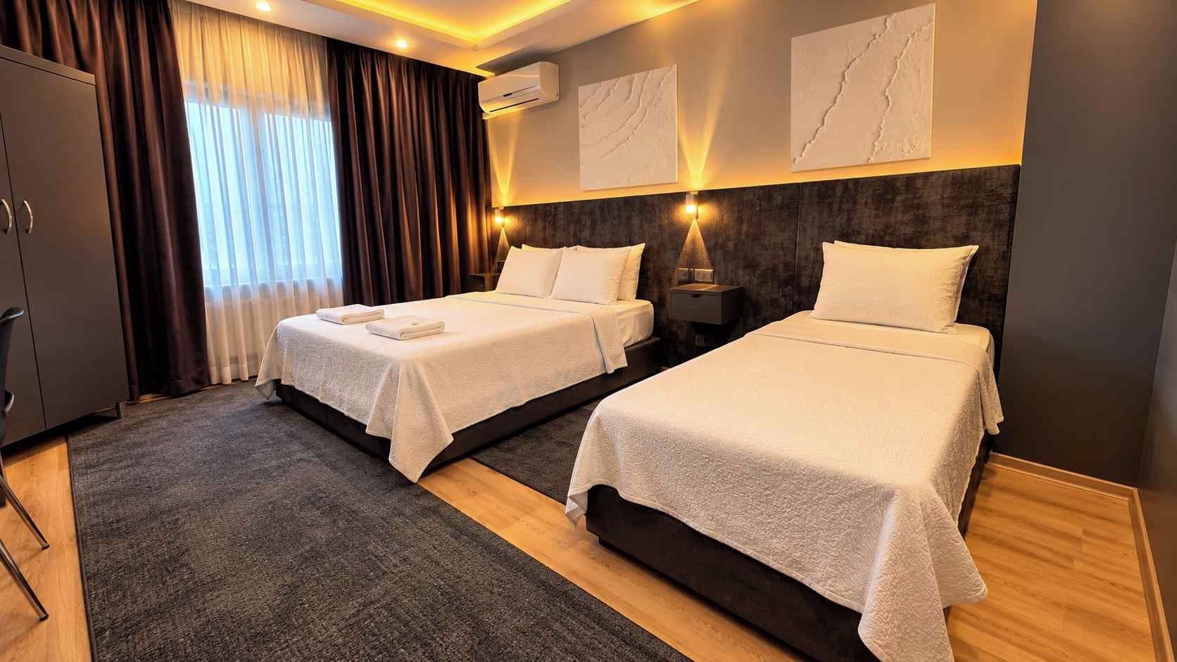 A hotel room with two beds, a desk, and a wardrobe.