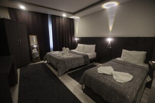 Una habitación de hotel con dos camas, un armario, un espejo y una mesita de noche.