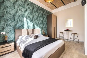 A bedroom with a large bed, a nightstand with a lamp, a mirror, and a small table with stools. - Roma Design San Giovanni Colosseo area (Rome)