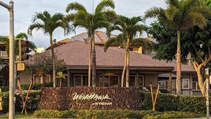 A hotel with a stone facade, palm trees, and a sign that reads "Wyndham by Wyndham."