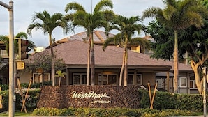 Een hotel met een gevel van natuursteen, palmbomen en een bord met de tekst 'Wyndham by Wyndham'.