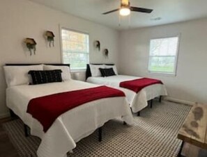 A room with two beds, each with white bedding and red throw blankets. There is a ceiling fan and two windows with blinds. - Charming 3-bedroom house in superb Farmington with WiFi, AC (Farmington)