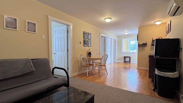 A living room with a sofa, a coffee table, and a dining area with chairs and a table. - Island Pond Apartment on VAST Trail – 2BR, 1BA (Brighton)