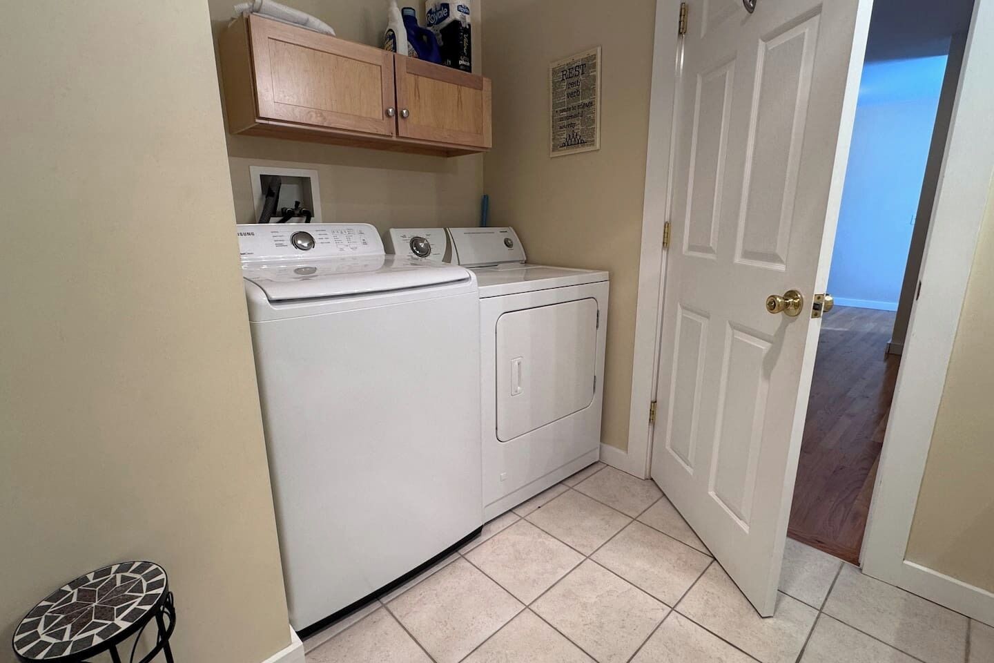 A laundry room with a washer and dryer, a small table, and a cabinet above the appliances.