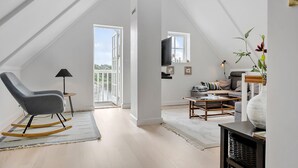 A spacious loft bedroom with a large window, a cozy seating area, and a television. - Awesome home in Gråsten with sauna (Gråsten)