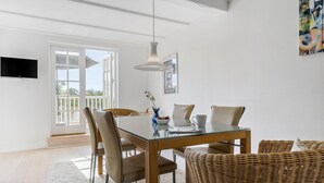 A dining area with a glass table, wicker chairs, a hanging light fixture, and a view through a glass door to an outdoor balcony. - Awesome home in Gråsten with sauna (Gråsten)