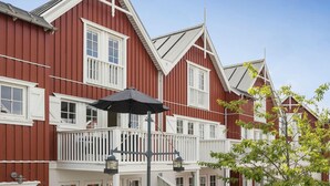 A red building with white trim, a balcony with a black umbrella, and a tree in the foreground. - Awesome home in Gråsten with sauna (Gråsten)