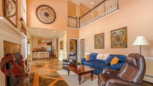 A spacious living area with a high ceiling, a fireplace, a dining area, and a staircase leading to an upper level. - Spacious 6-Bedroom Mountain Home –Minutes from Park City’s Year-Round Adventures (Kamas)