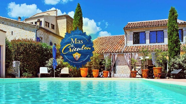 Une piscine d’hôtel avec un panneau indiquant « Mas Creuilon » et un bâtiment en pierre doté de portes bleues.