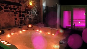 Un bain à remous avec des bougies et un mur en pierre.