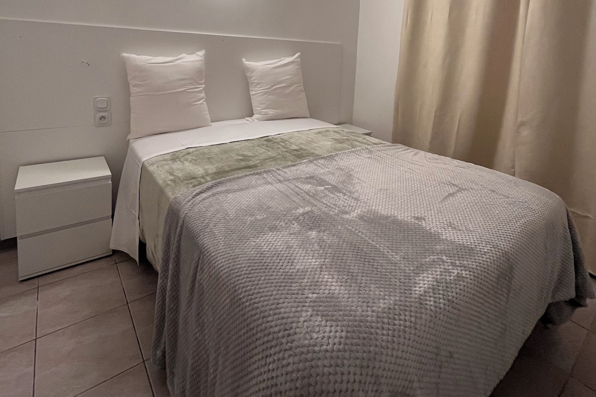 Une chambre à coucher avec un lit, une table de chevet et une lampe fixée au mur.