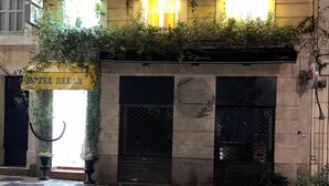 A building with a sign reading "HOTEL RELAX" and "HOTEL" above it. There are potted plants on the ground floor and a sign for "Daymé IOPERA" on the facade. - Hotel Relax (Marseille)
