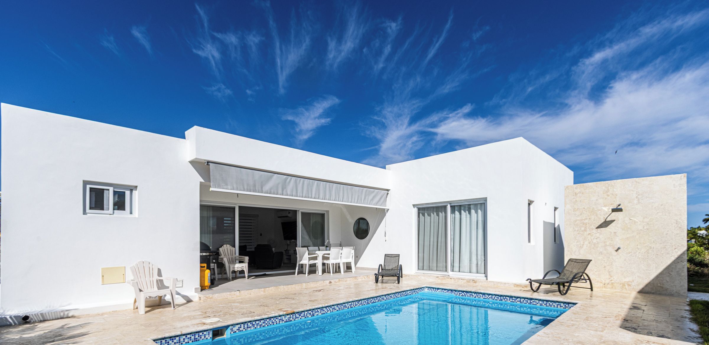 A modern house with a swimming pool, white exterior walls, and a covered patio area.