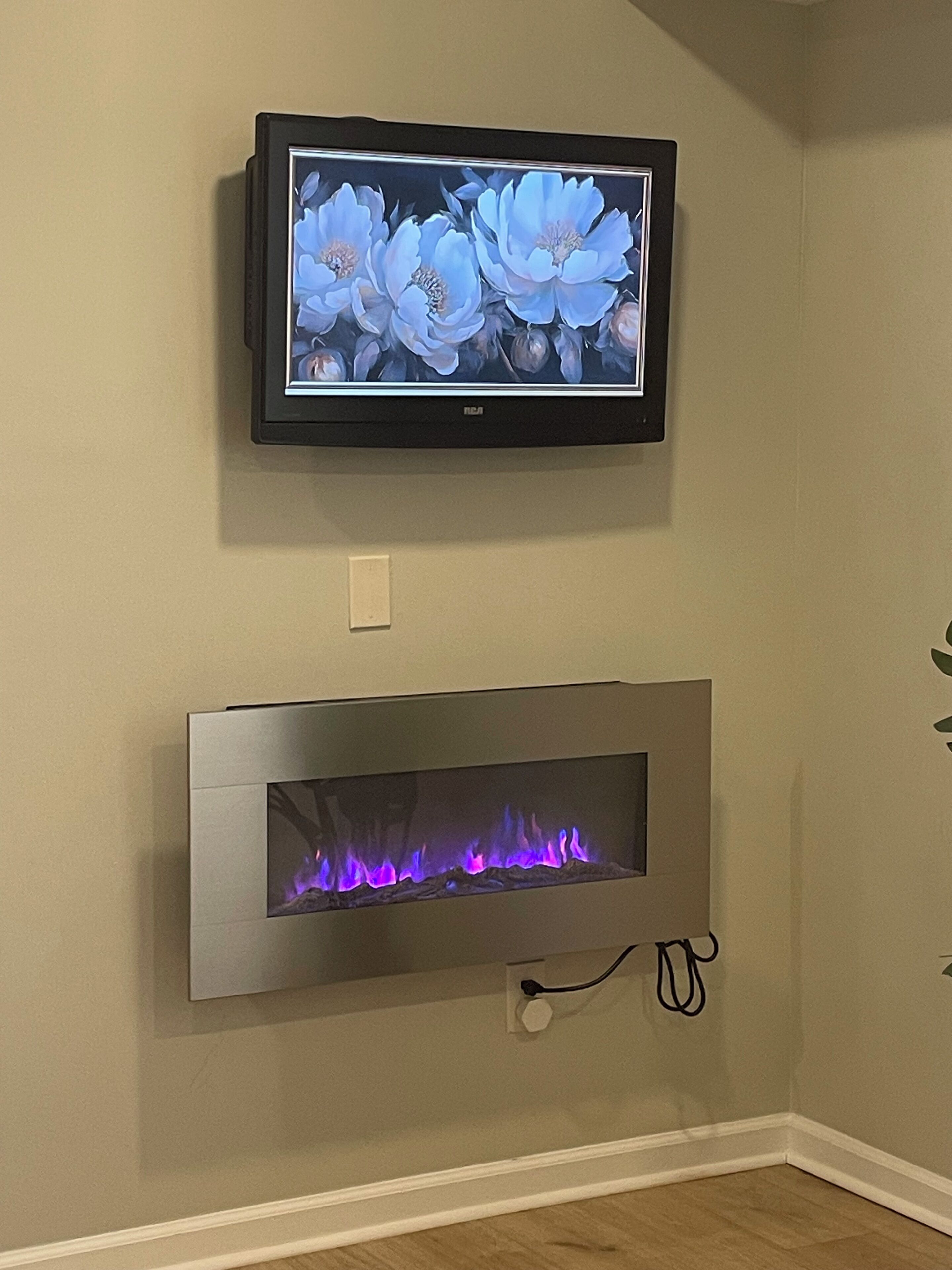 A wall-mounted television and a fireplace with a visible flame.