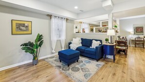 A living room with a blue sofa, a matching ottoman, a coffee table, a potted plant, and a patterned rug. - Chic 1-bedroom with WiFi and AC in fabulous Alpharetta - Blue Gate (Alpharetta)