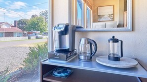 Eine Küchenzeile mit Kaffeemaschine, Wasserkocher und French Press auf einer Arbeitsfläche.