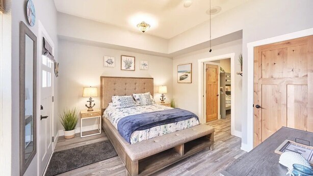 Ein Schlafzimmer mit Bett, Nachttischen, einer Bank, einem Deckenventilator und einer Tür.