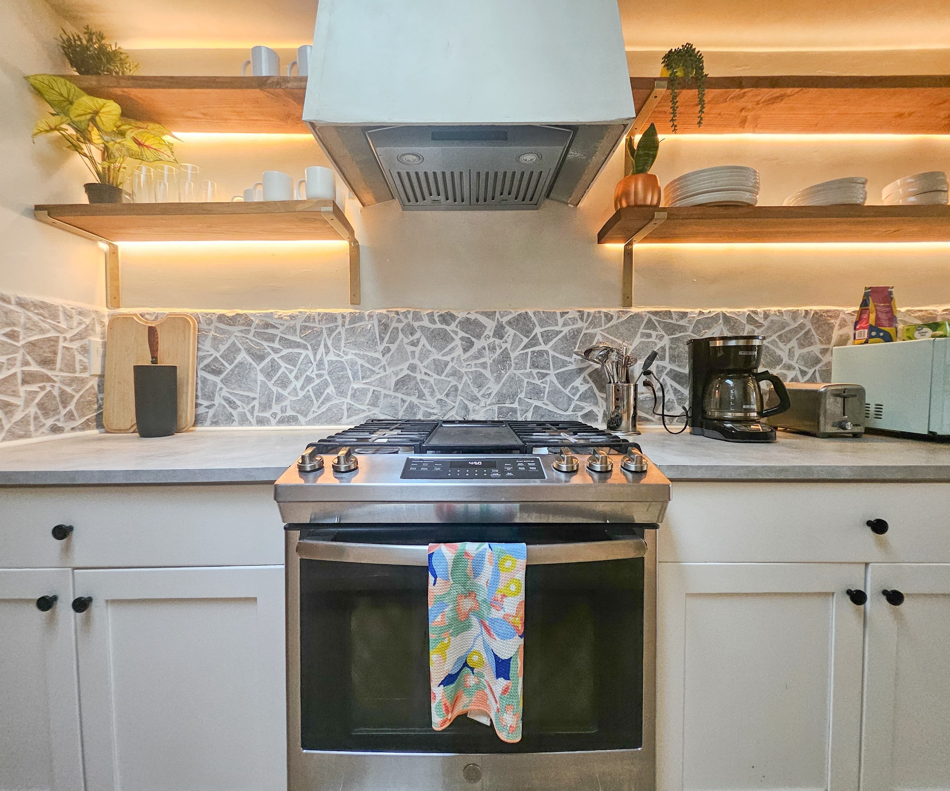 Cocina moderna con estufa a gas, horno y cafetera.
