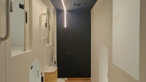 A modern, minimalist bathroom with wooden accents and a sloped ceiling. - Brimfield Stay (Panorama City)