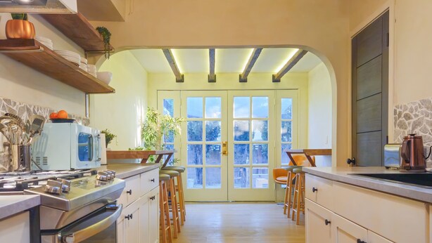 A kitchen with wooden cabinets, a stainless steel oven, and a hanging light fixture. - Brimfield Stay (Panorama City)