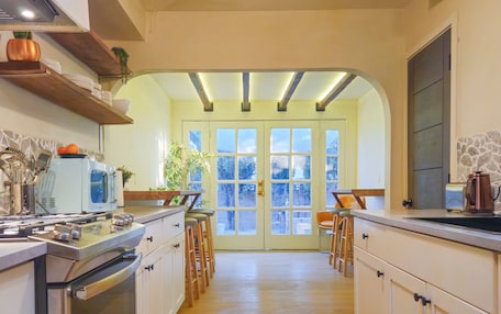 A kitchen with wooden cabinets, a stainless steel oven, and a hanging light fixture.