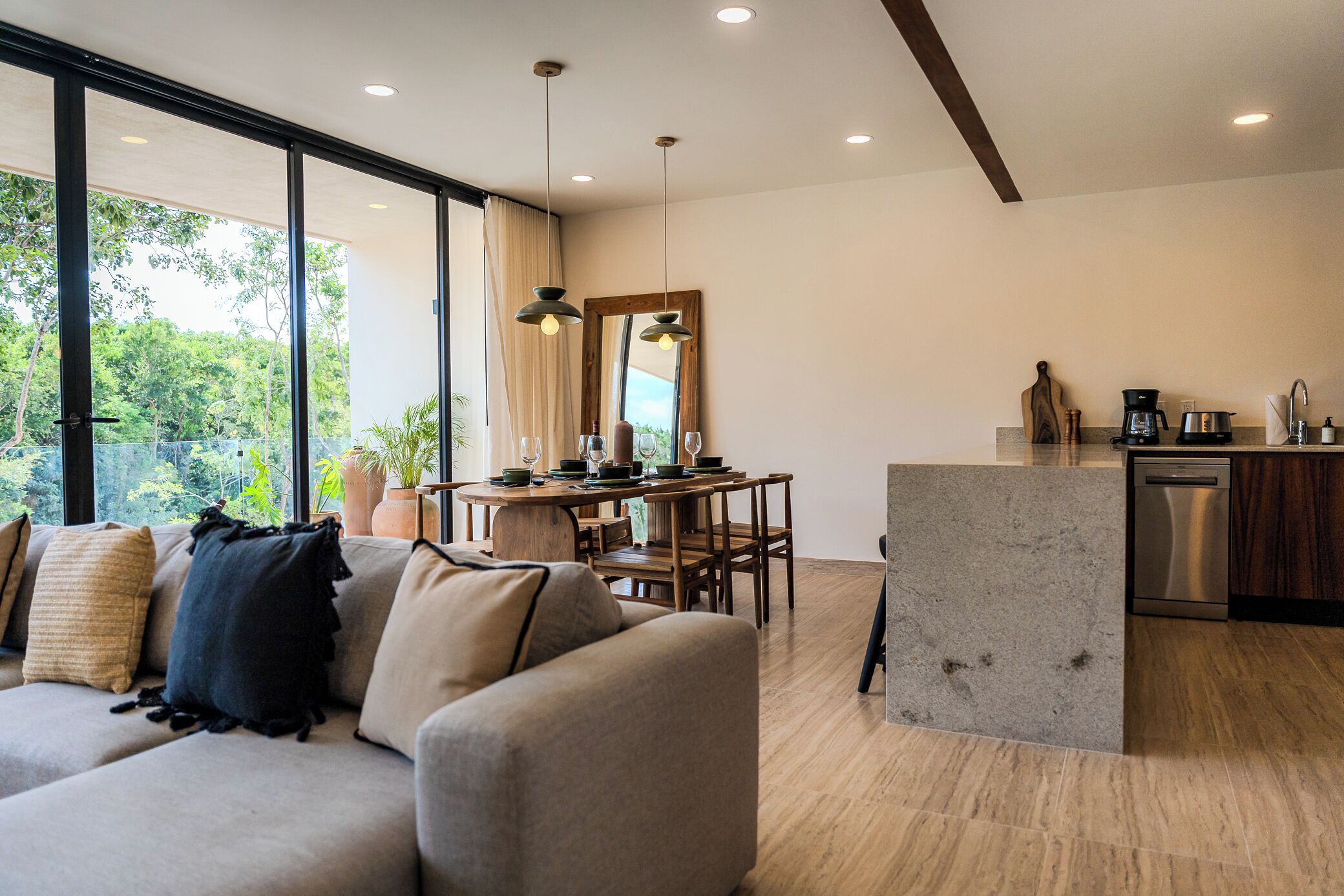 A modern living room with a sofa, dining table, and kitchen area.
