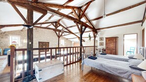 A rustic room with exposed wooden beams, a loft bed, a desk, and a stone wall. - Nice home in Saint-Simon with private swimming pool, can be inside or outside (Saint-Simon)