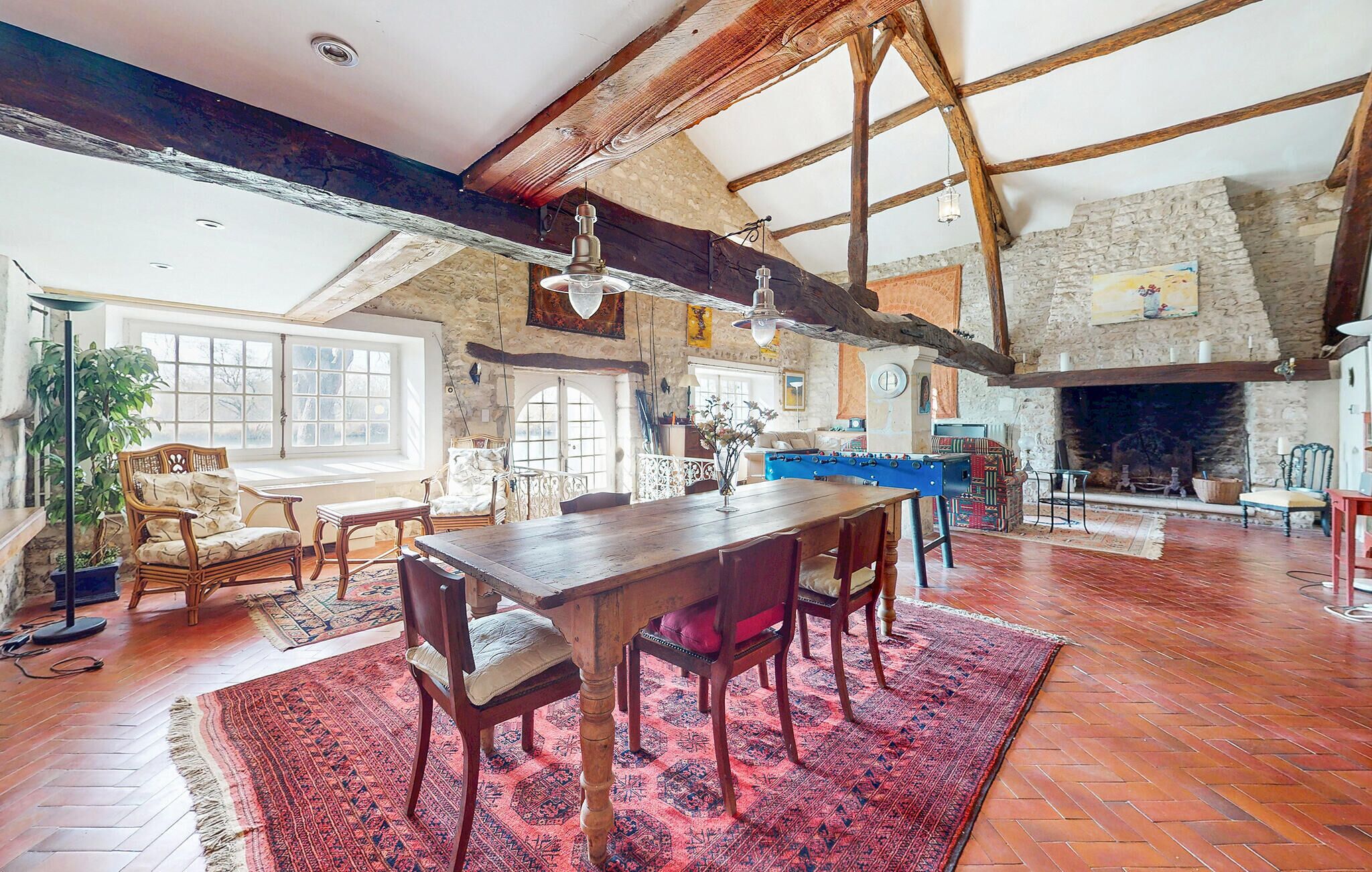Une pièce spacieuse avec une table et des chaises en bois, une cheminée et un mur en pierre.