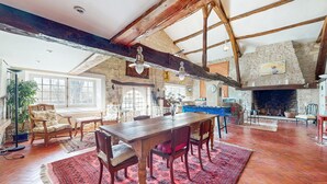 A spacious room with a wooden table and chairs, a fireplace, and a stone wall. - Nice home in Saint-Simon with private swimming pool, can be inside or outside (Saint-Simon)
