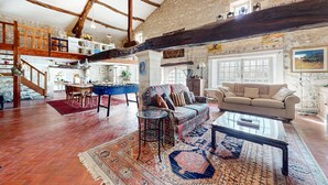 A spacious living area with a high ceiling, exposed wooden beams, a stone wall, and a cozy seating arrangement including a sofa and a coffee table. - Nice home in Saint-Simon with private swimming pool, can be inside or outside (Saint-Simon)