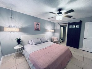 Relax in this serene bedroom featuring a large bed and ceiling fan.