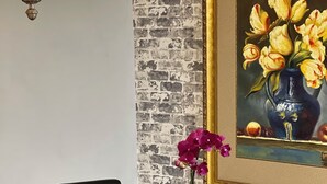 A dining area with a brick-patterned wall, a framed painting of flowers, a table with chairs, and a hanging light fixture. - Charming 2BE/2BA condo on Preston in Dallas (Dallas)