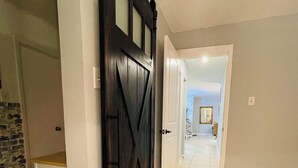 A hallway with a dark wooden door, white walls, and beige tiled flooring. - Charming 2BE/2BA condo on Preston in Dallas (Dallas)