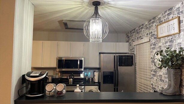 A modern kitchen with a chandelier, stainless steel appliances, and a brick wall. - Charming 2BE/2BA condo on Preston in Dallas (Dallas)