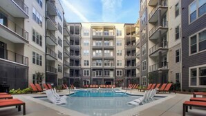 A modern apartment building with a central courtyard featuring a swimming pool and lounge chairs. - 2 Bedroom Buckhead Suite (Atlanta)