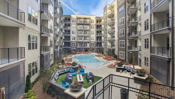 A multi-story residential building with balconies, a central courtyard with a swimming pool, outdoor seating, and greenery. - 2 Bedroom Buckhead Suite (Atlanta)