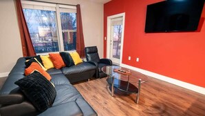 A living room with a sectional sofa, a glass coffee table, and a red accent wall. - 2 Bedroom Buckhead Suite (Atlanta)