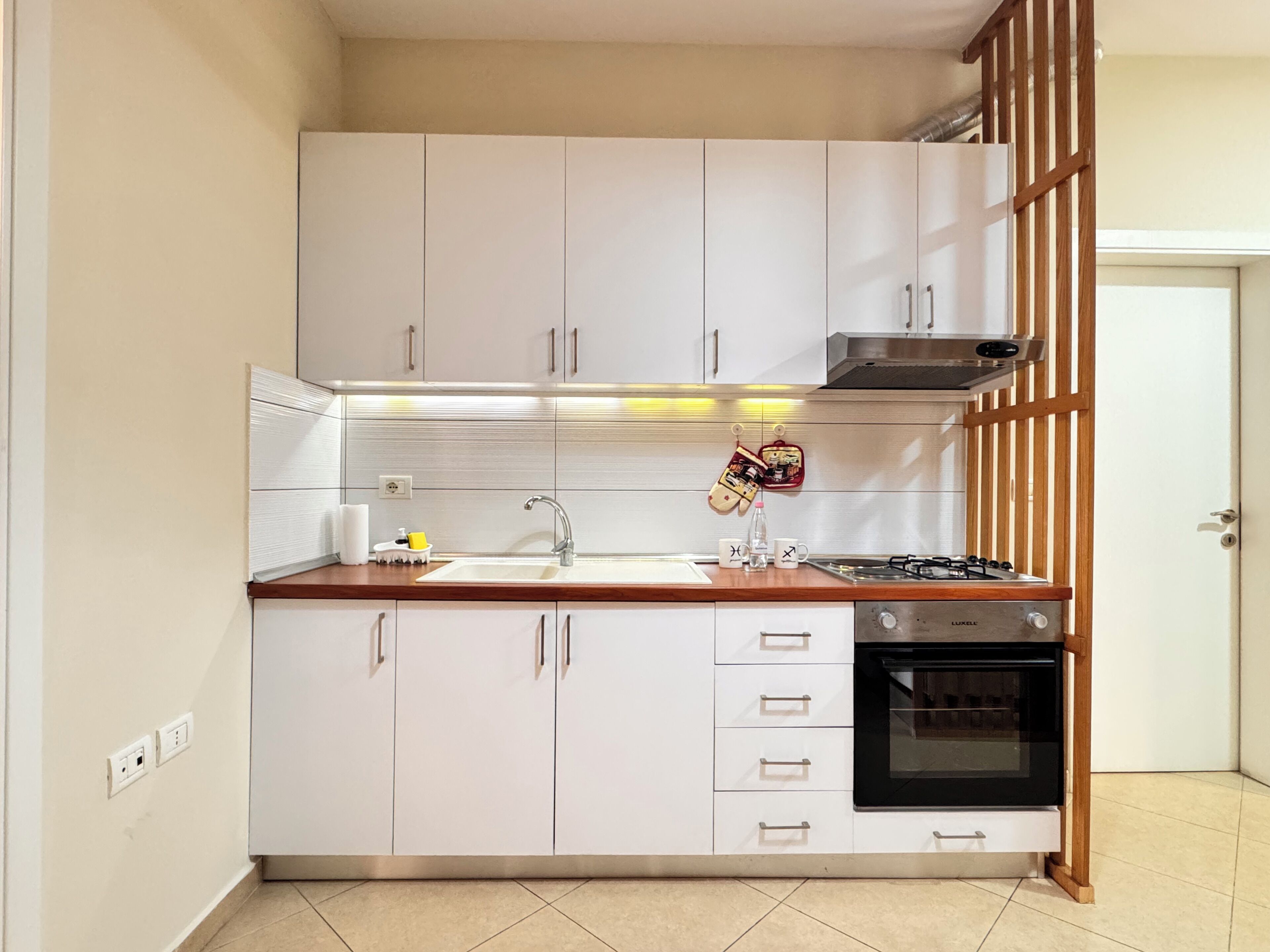 A modern kitchen with white cabinets, a stainless steel sink, a gas stove, and a built-in oven.