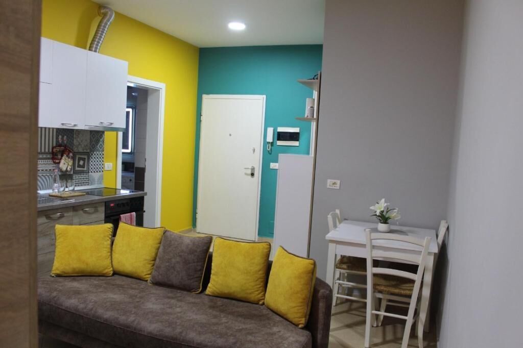 Un espace de vie compact comprenant un canapé, une table à manger avec des chaises et un coin cuisine.