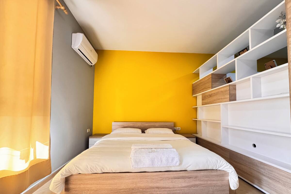 A bedroom with a bed, a wardrobe, and an air conditioning unit.