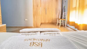 A hotel room with a bed, a wooden wardrobe, a small table with a chair, and a window with curtains. - BSB Apartment  (Tirana)