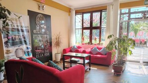 A hotel lobby with red sofas, a coffee table, potted plants, and a large poster on the wall. - Hotel Golden Killa (Huaraz)