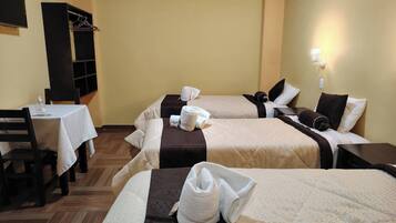 Habitación de hotel con dos camas, una mesa, una silla y un armario.