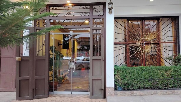 A hotel entrance with a decorative metal gate, a glass door, and a large sun-like artwork on the wall. - Hotel Golden Killa (Huaraz)