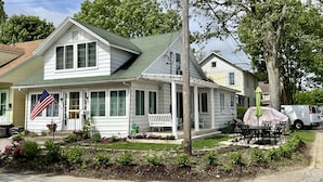 Une maison à deux étages avec un porche, un drapeau et un espace extérieur aménagé avec des sièges.