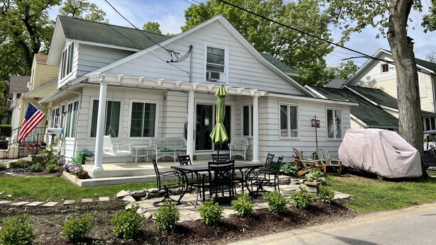 Une maison à deux étages dotée d’un patio couvert et de mobilier d’extérieur.
