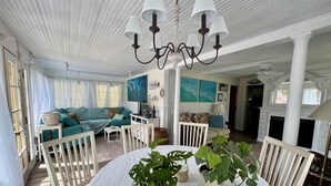 Un salon spacieux avec un plafond blanc, une table ronde agrémentée de plantes en pot, un canapé de couleur turquoise et une rambarde blanche.
